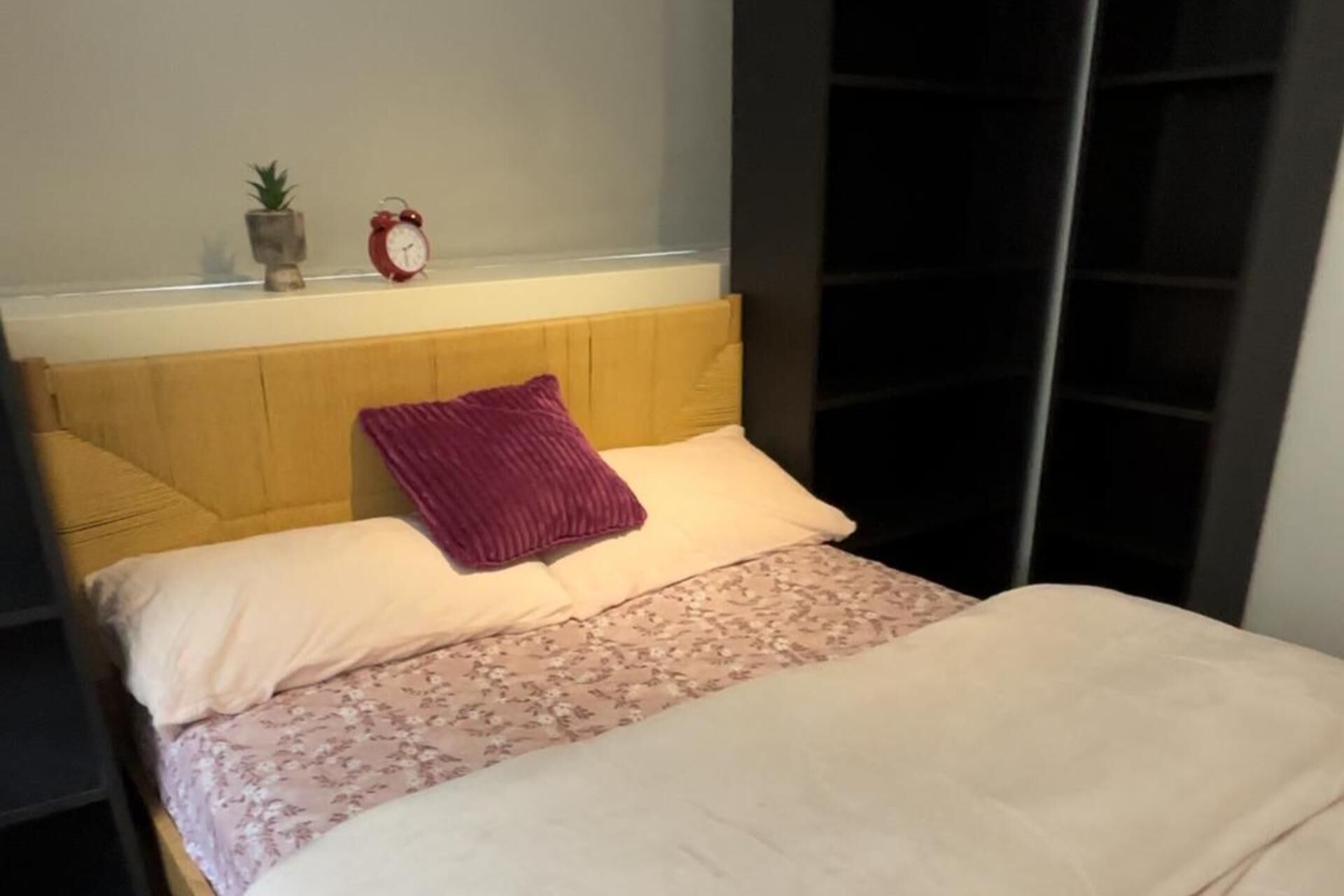 Una cama con cabecera de madera, colcha estampada y dos almohadas.