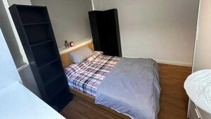 A small, compact bedroom with a single bed, a bedside table, and a wardrobe. - Charming Studio in Bond Street (London)