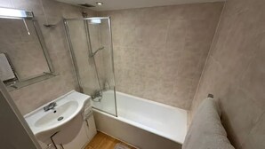 A modern bathroom with a glass-enclosed shower, a white sink, and a bathtub. - Charming Studio in Bond Street (London)