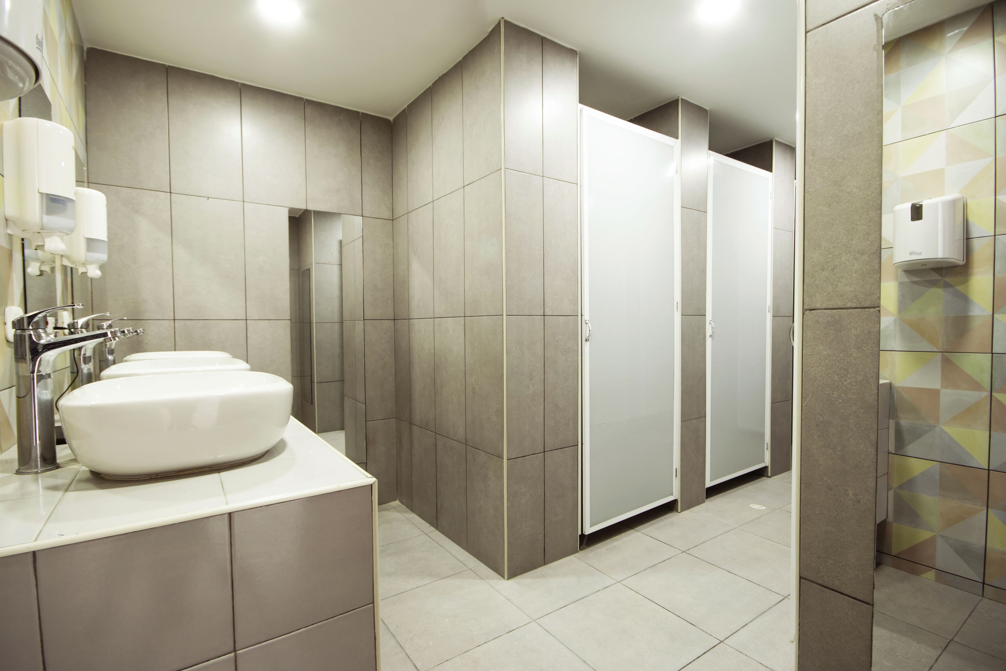 A modern bathroom with a large sink, a mirror, and a toilet stall.