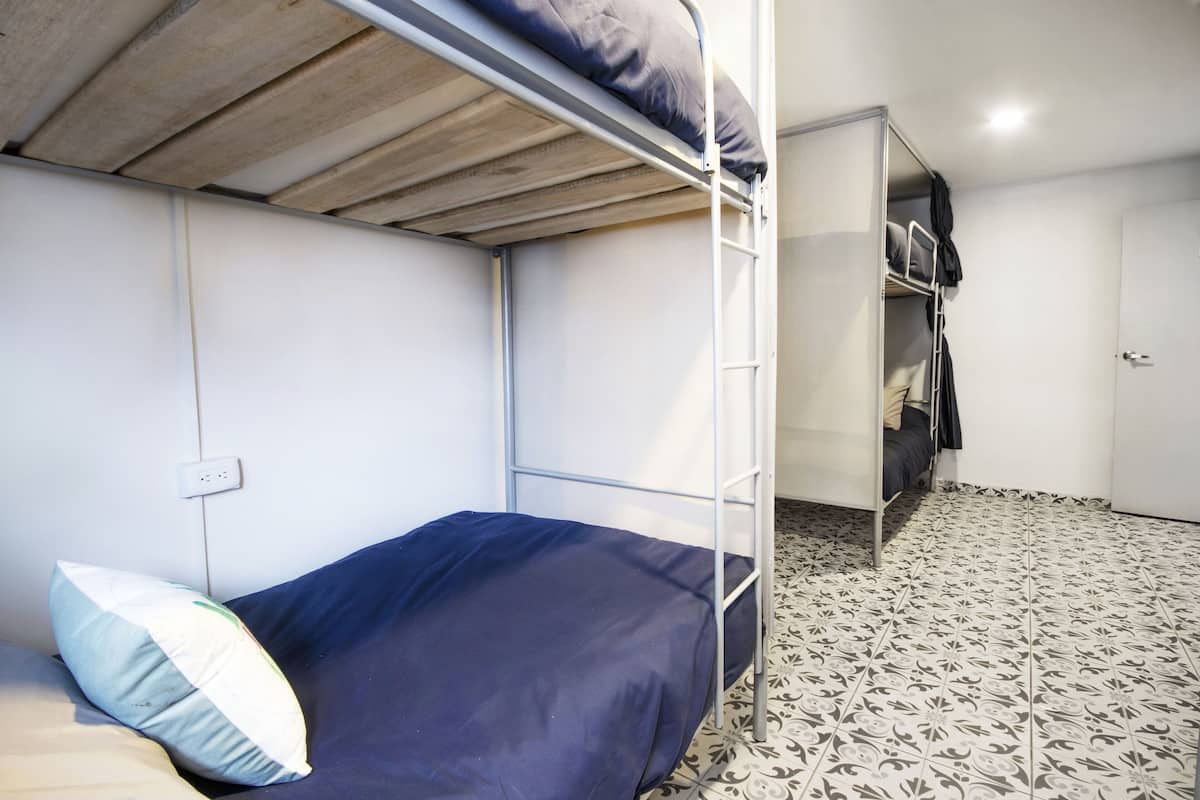Una cama individual superpuesta con colchón y almohadas, un armario y un suelo con diseño.