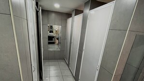 A narrow hallway with tiled floors and walls, leading to a bathroom area with a sink and mirror. - Urbana Hostel (Bogotá)