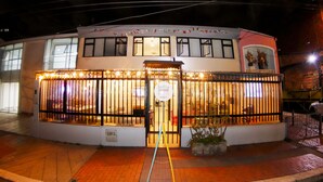 A two-story building with a gated entrance, large windows, and a small balcony with plants. - Urbana Hostel (Bogotá)