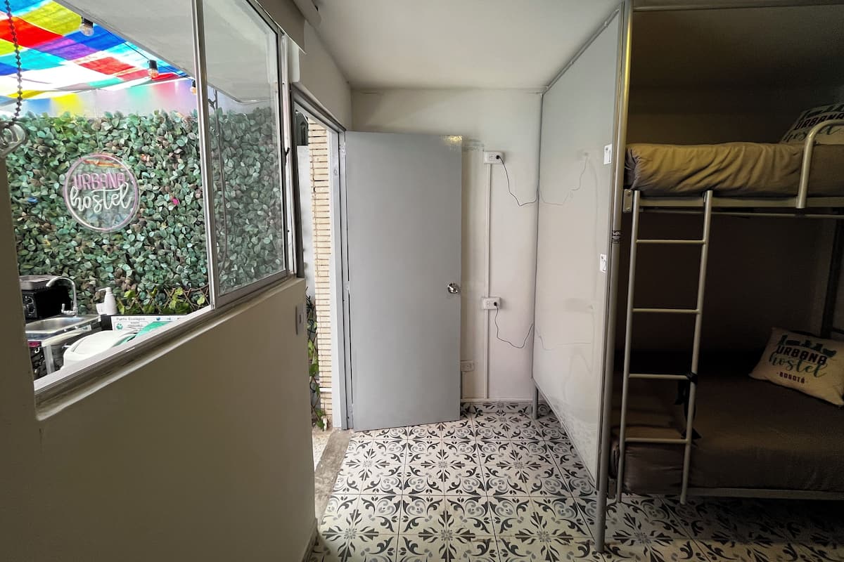 Una habitación pequeña con literas, un kitchenette reducido y un ventanal con techo colorido.