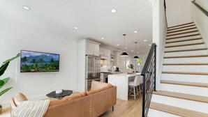 A modern kitchen with white cabinets, a dining area with a table and chairs, and a staircase leading to an upper floor. - Gorgeous Newly Built 3BR Home in Alexandria (Alexandria)