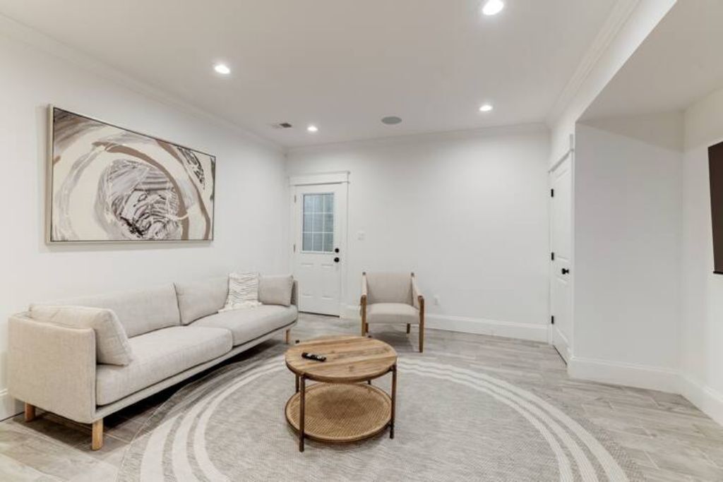 A modern living room with a sofa, a chair, a coffee table, and a large abstract painting on the wall.