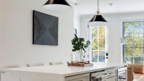 A modern kitchen with a marble island, pendant lights, and a view of the outdoors. - Gorgeous Newly Built 3BR Home in Alexandria (Alexandria)