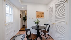 Ein Essbereich mit einem runden Tisch, zwei Stühlen, einer Blumenvase und einem gerahmten Bild an der Wand.