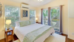 A bedroom with a large bed, two bedside tables, a ceiling fan, and a window with curtains. - ‘The Hammock Cottage’ w/ Fire Pit < 1 Mi to Beach! (Palm Coast)