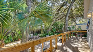 A wooden deck with a railing, surrounded by lush greenery and trees. - ‘The Hammock Cottage’ w/ Fire Pit < 1 Mi to Beach! (Palm Coast)