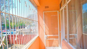 A narrow balcony with a metal railing, a door, and a window with a mesh screen. - Fantastic Location, 1-bed Apartment in Harare (Harare)