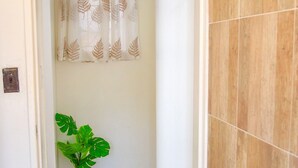 A narrow hallway with a potted plant, a door leading to another room, and a tiled wall. - Fantastic Location, 1-bed Apartment in Harare (Harare)