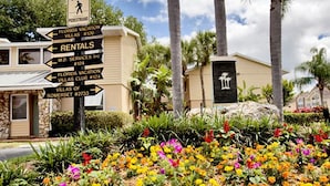 Un cartel con indicaciones a diferentes lugares, incluyendo Florida Vacation Villas #126, Alquileres y M.D. Services Inc. #124.