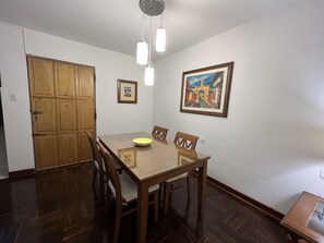 Un comedor con una mesa y sillas de madera, un cuenco sobre la mesa y un cuadro en la pared.