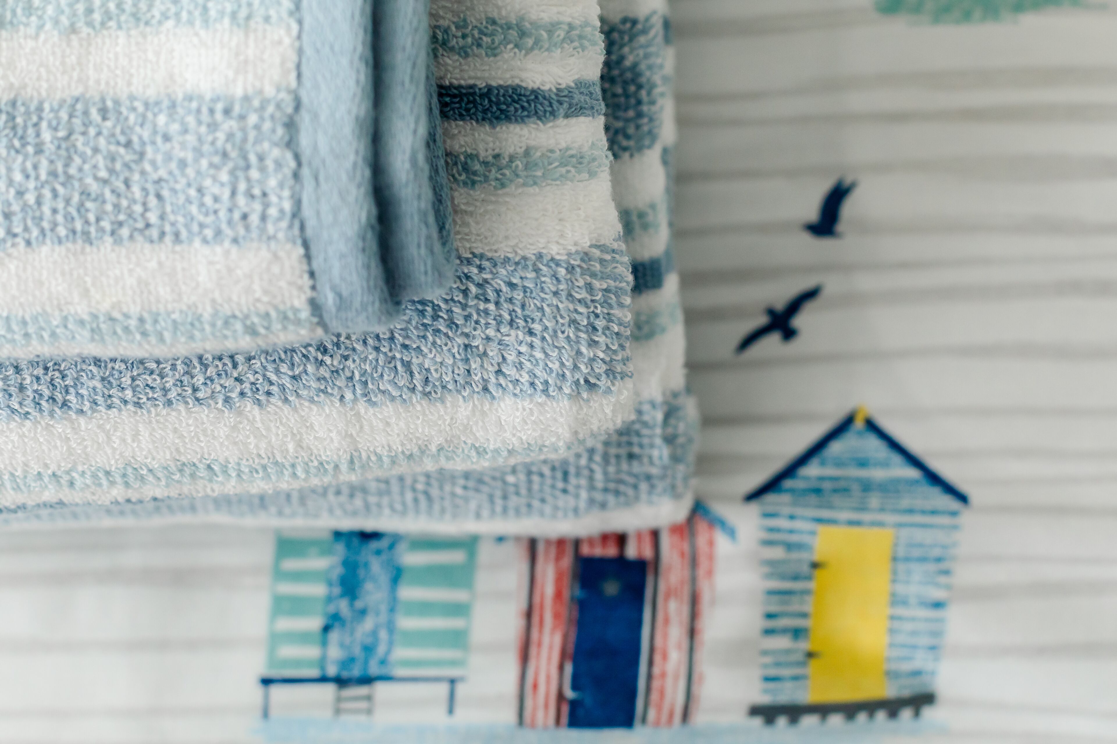 Un tissu à rayures orné d’une maison et d’oiseaux.