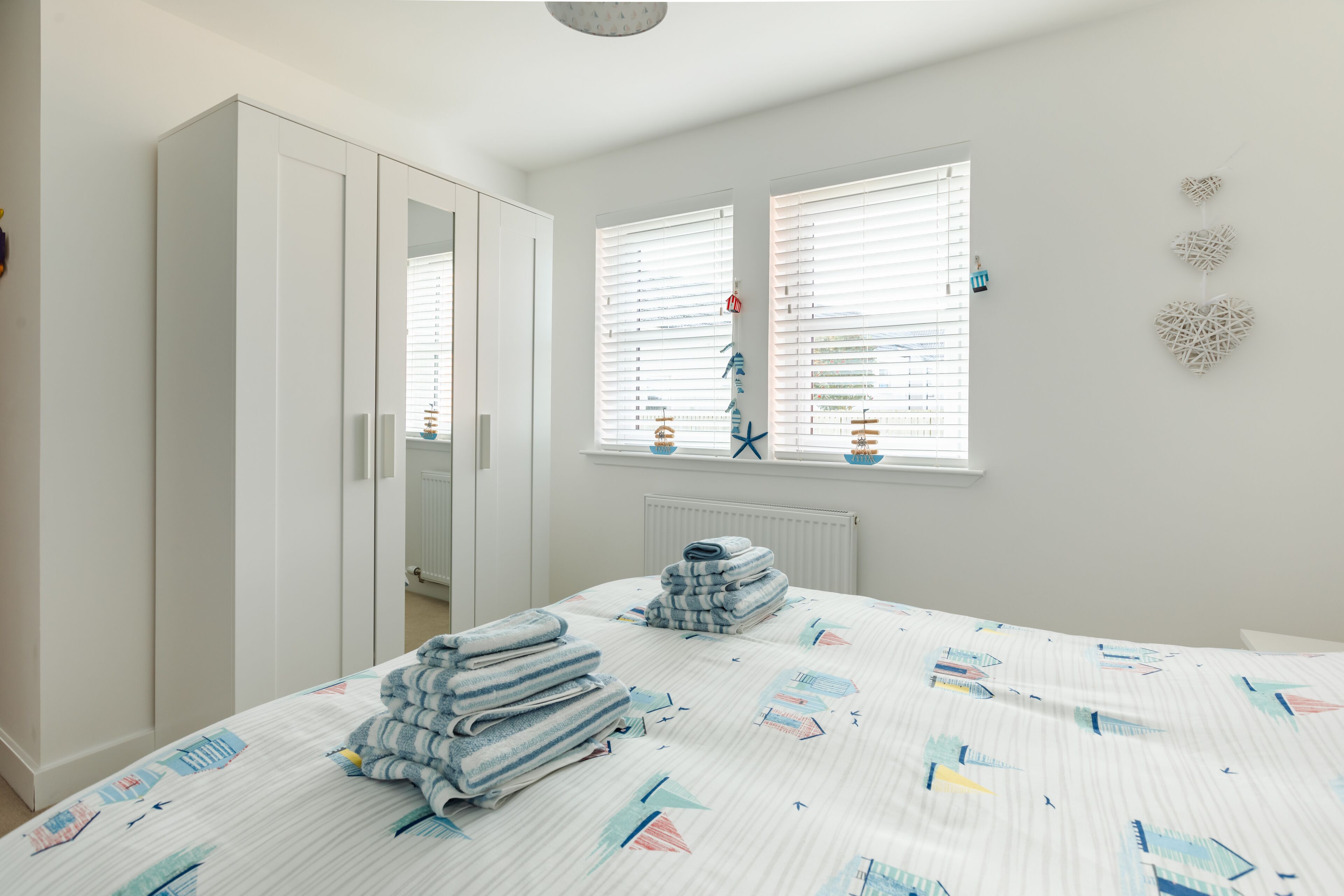 A bedroom with a bed, a wardrobe, a radiator, and a window with blinds.
