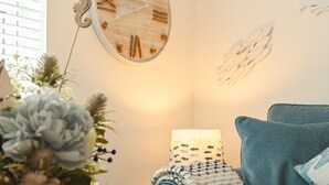 A cozy room with a blue sofa, a wall clock, and a lamp.