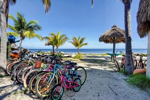 A beach with bicycles parked near palm trees and a thatched umbrella. - Key Largo Townhouse Next to Pool and Salt Water Lagoon in Gated complex (Key Largo)
