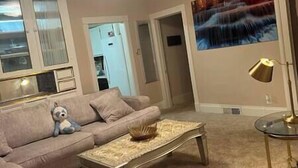 Ein Wohnzimmer mit einem beigefarbenen Sofa, einem Glastisch und einem Bild an der Wand.