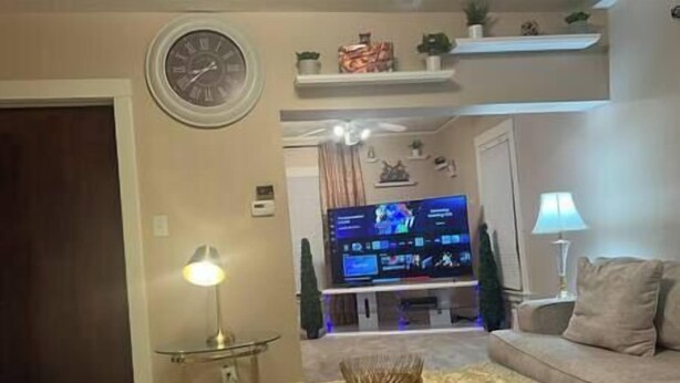 Ein Wohnzimmer mit Flachbildfernseher, Couchtisch mit dekorativer Schale, Lampe und Sofa.