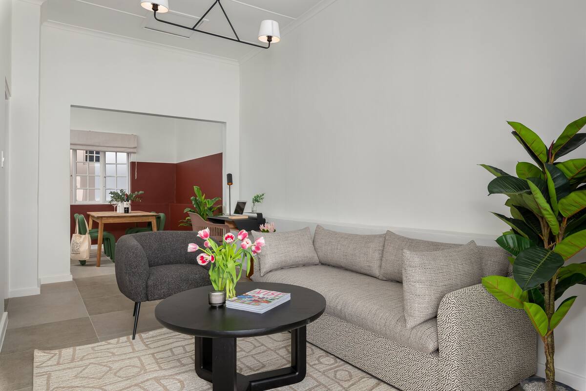 A modern living room with a grey sofa, a round black table, and a potted plant.
