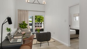 A modern living room with a laptop, a desk, a chair, a sofa, a coffee table, and a potted plant. - Neighbourgood Franschhoek (Franschhoek)
