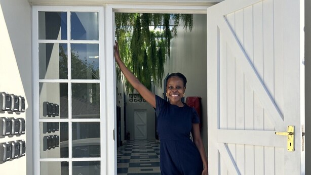 A person standing at the entrance of a building with a checkered floor and a door with a diagonal design. - Neighbourgood Franschhoek (Franschhoek)