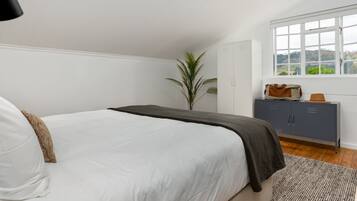 Un dormitorio con cama, armario, ventana con vistas y una planta.