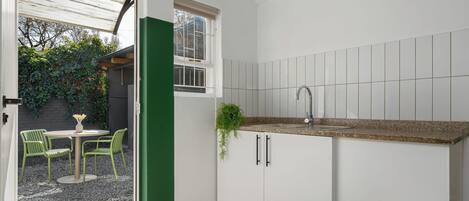 Cocina con armarios blancos, encimera de granito y ventana con vistas al exterior.