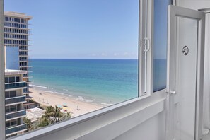 Uitzicht op een strand vanuit een hotelkamer, met een heldere lucht.