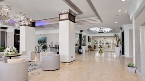A spacious lobby with modern furniture, a chandelier, and a large window.