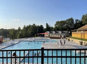 A swimming pool with multiple lanes, surrounded by a fence. There are people swimming and lounging around. - Pocono Getaway with Deck & Fire Pit + Community Pool Access – Sleeps 6 (Tobyhanna)