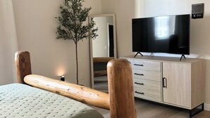 Una camera da letto con un letto, una testiera in legno, un comò con televisore e uno specchio.