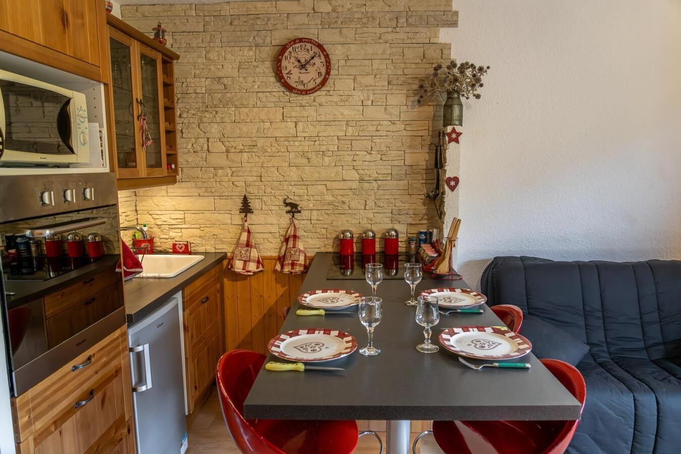A kitchen with a dining table set for four, a microwave, cabinets, and a brick wall.