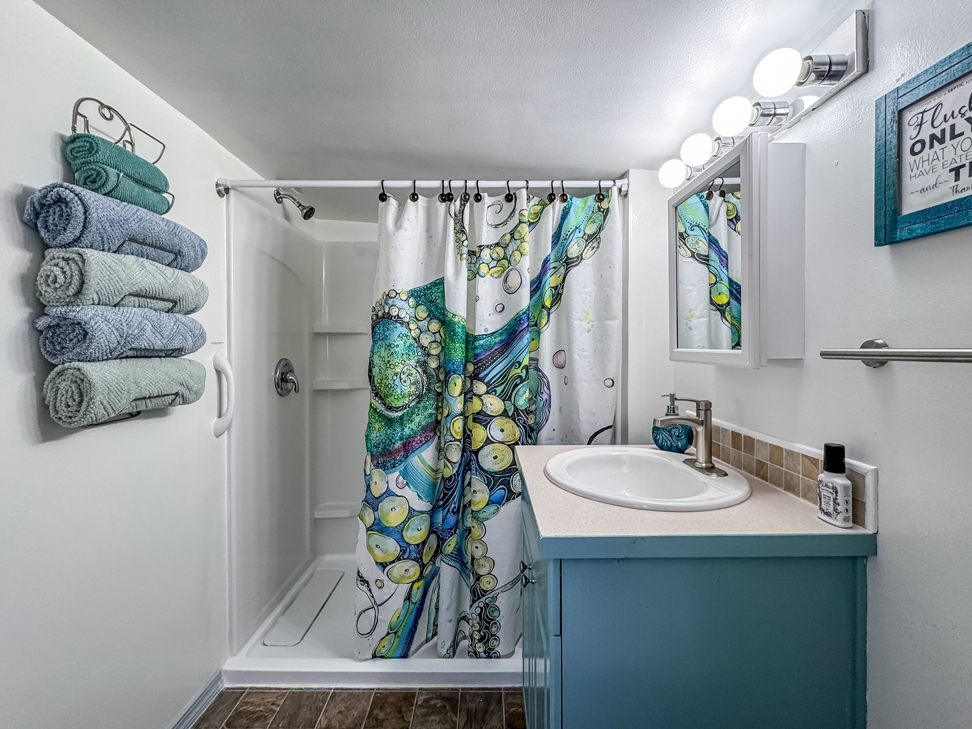 Une salle de bain avec un rideau de douche, un lavabo, un miroir et des serviettes.