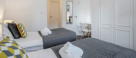 Une chambre d’hôtel avec deux lits, une chaise, un bureau et une porte.