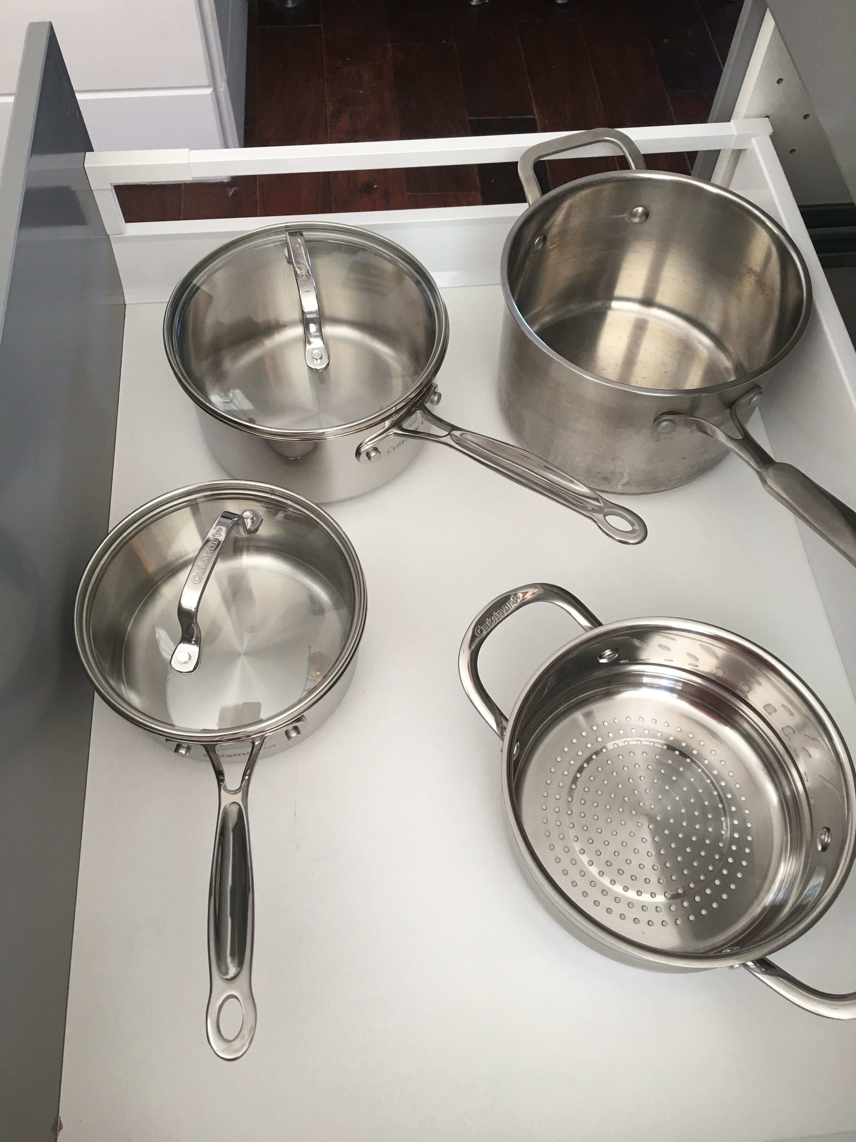 Un calaix de cuina amb quatre olles i paelles d'acer inoxidable.