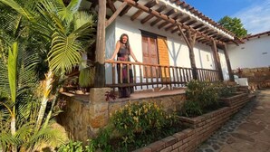 A traditional house with a wooden porch, stone walls, and a tiled roof.