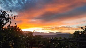 A sunset view with mountains in the background and a garden area in the foreground.