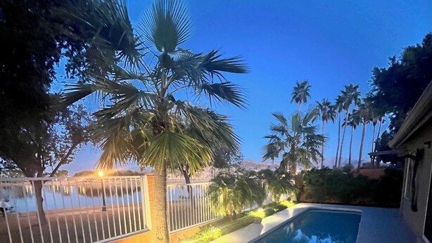 A swimming pool with a metal railing, surrounded by palm trees and a fence. - Lake House Pool & Palms (Goodyear)