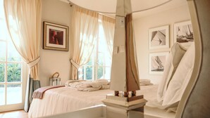 Une chambre avec un grand lit, une table de chevet, une fenêtre avec des rideaux et des tableaux encadrés accrochés au mur.