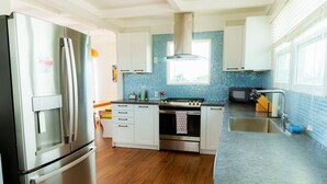 Een moderne keuken met roestvrijstalen apparatuur, witte kasten en een blauwe tegelachtergrond.