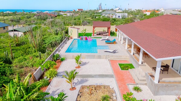 A residential property with a swimming pool, outdoor seating, and a view of the ocean.