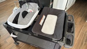 Een inklapbare kinderwagen met een bekleed dienblad en autostoeltje.