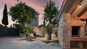 A stone patio with a built-in fireplace, outdoor seating, and a large tree. - Villa Pietrissima with Pool (Kanfanar)