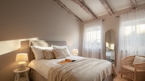 A bedroom with a large bed, bedside lamps, a wicker chair, and a mirror. - Villa Pietrissima with Pool (Kanfanar)