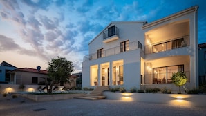 A modern two-story house with a balcony, outdoor seating, and a well-lit entrance. - Villa Oasi di Sogno with Pool (Biograd na Moru)
