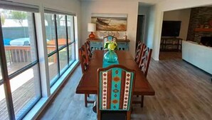 A dining area with a wooden table and chairs, large windows, and a view of the outdoors. - Beautiful lakefront home new to market (Hot Springs)