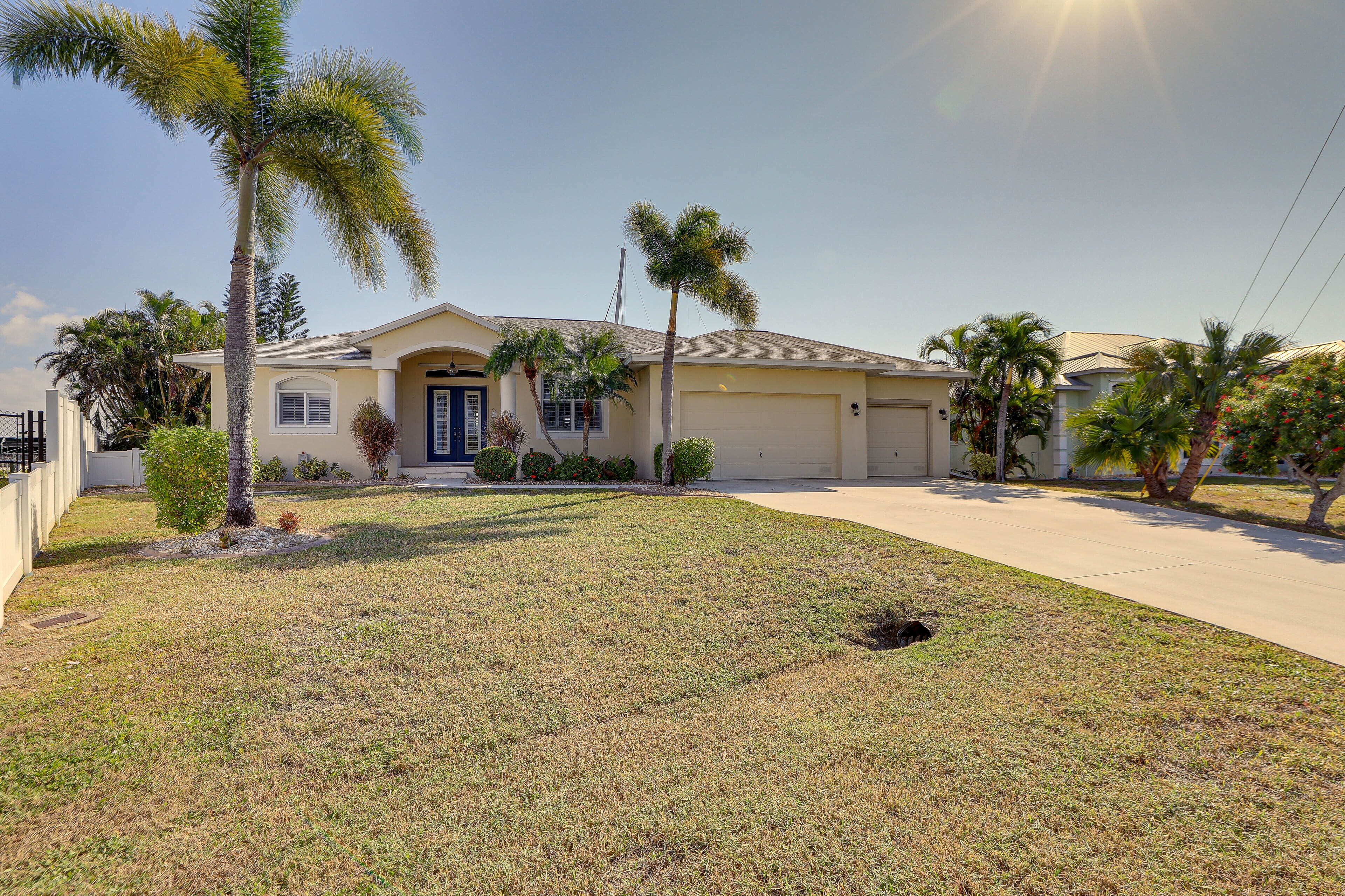 A single-story house with a front yard, palm trees, and a garage.