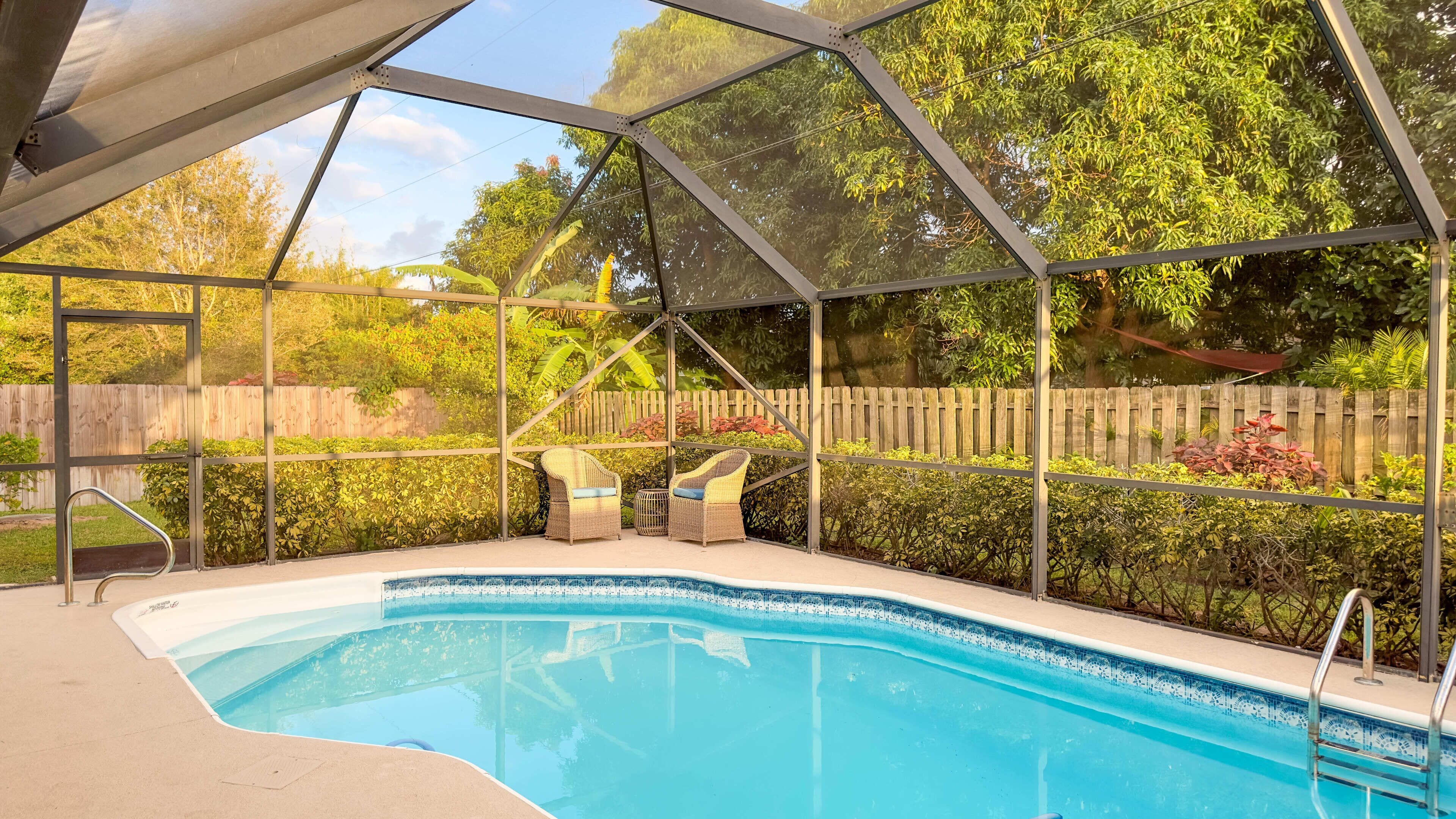Una piscina techada con dos sillas de mimbre y una escalera.